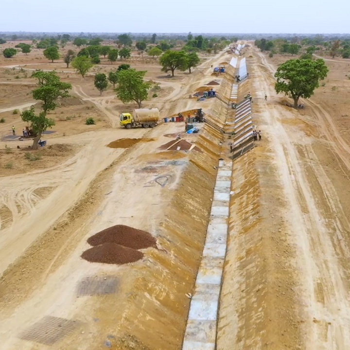 In the middle of a wide arid landscape with a few trees a trench in construction for the northern extension of the Tiékélinso North Perimeter in the San-Ouest Plain, Mali.