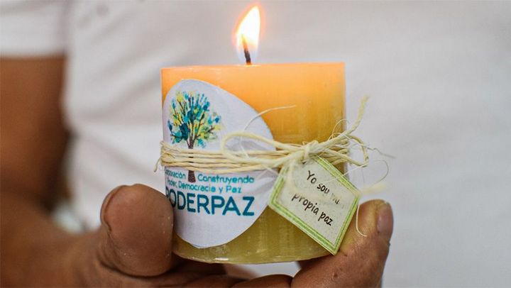 A hand holding a lighted candle for peace in Colombia.