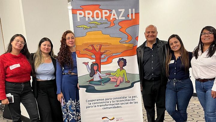 The project team for ProPaz II in Colombia posing around a project bannerd during the Col-Col conference.