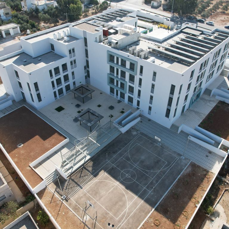 Bird view of modern school building with solar panels on the roof and external recreational areas.