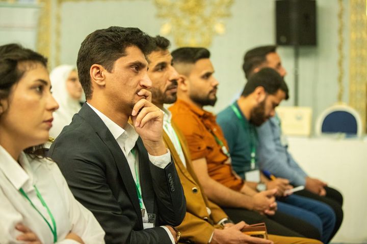 A row of young people sitting in the audience during a graduations ceremony.