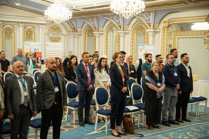 The audience standing in during an official graduation ceremony.